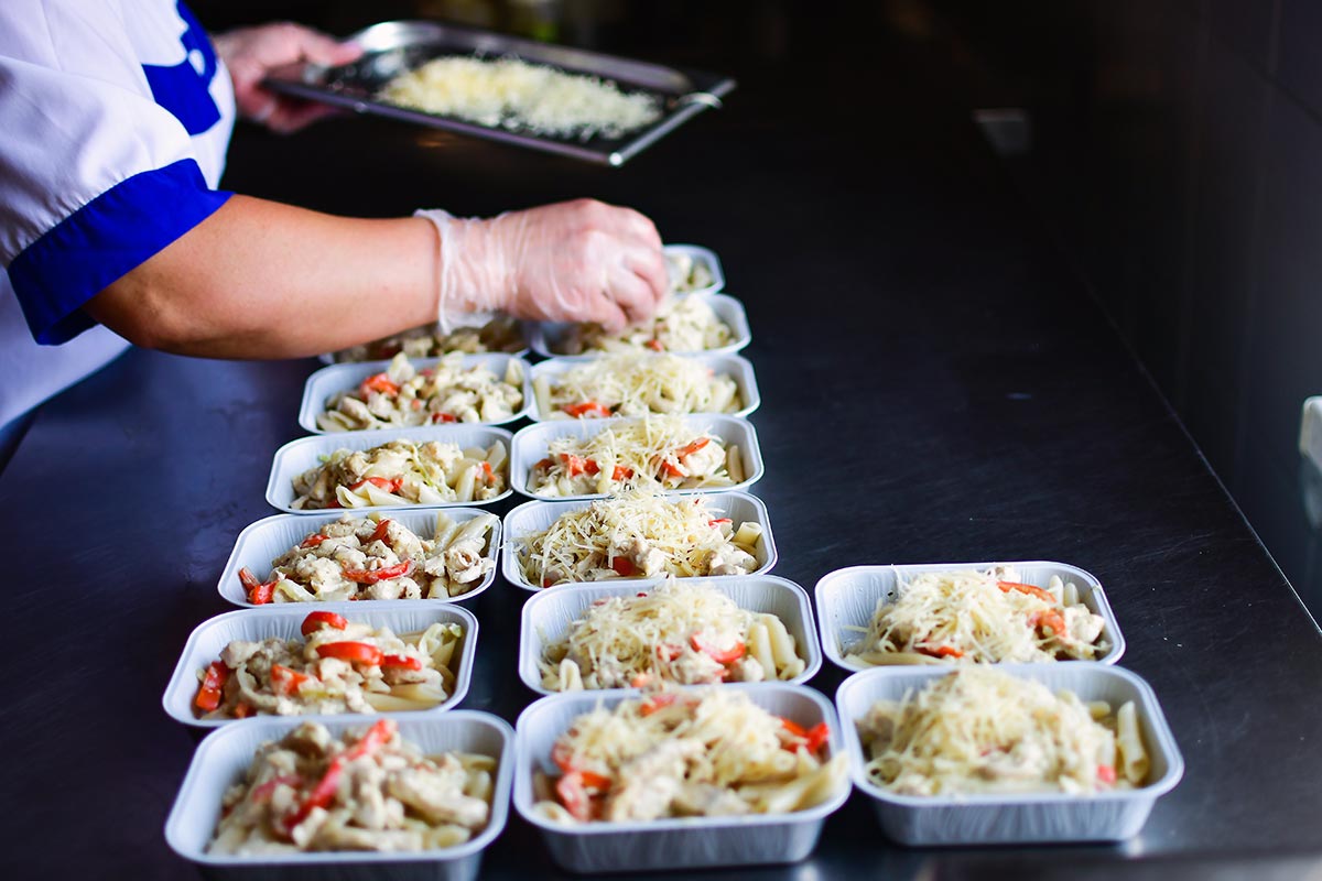 Une personne prépare des plats prêts à être congelés pour les popotes